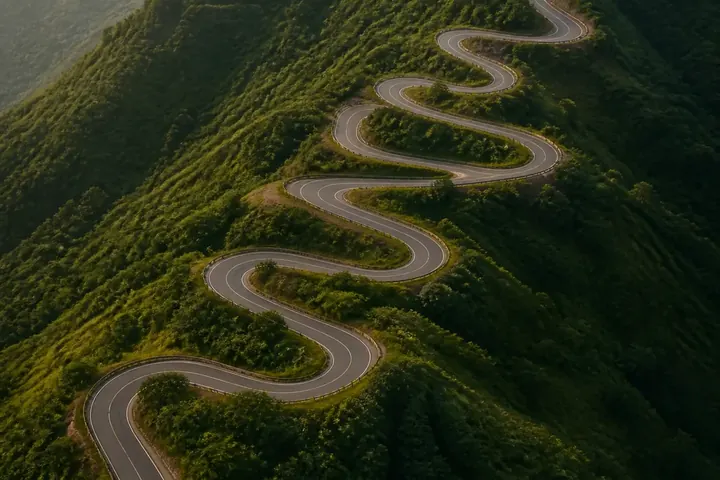 indirect meaning picture: A winding mountain road seen from above, curving back and forth instead of going straight